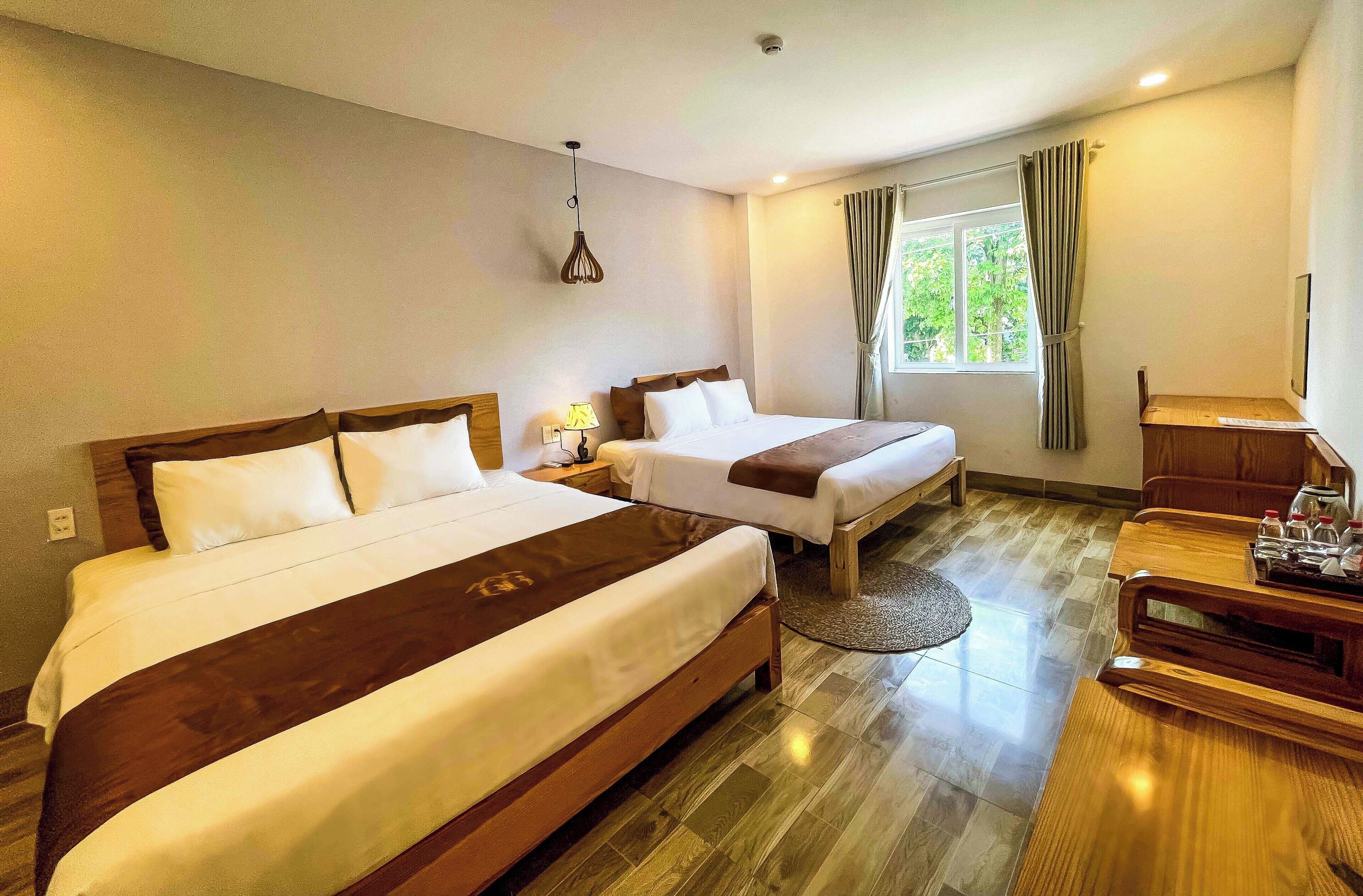 A hotel room with two beds, a desk, and a window with curtains.