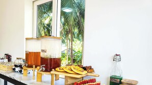 A kitchen counter with a large coffee maker, a fruit display, and a bottle of juice.