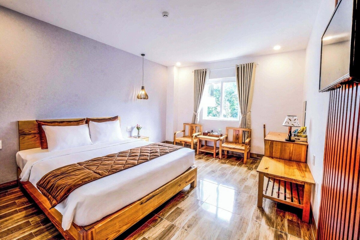 Una habitación de hotel con cama, escritorio, silla y televisor.