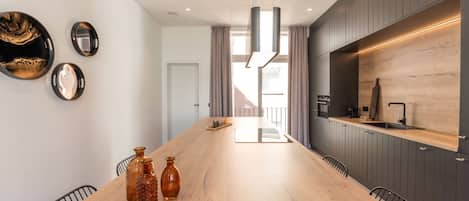 Una cocina moderna con encimera de madera, armarios oscuros y una gran mesa de comedor.