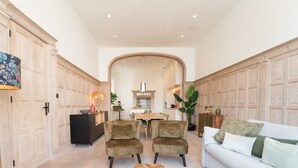 A spacious living room with a sofa, two armchairs, a coffee table, and a dining area in the background.