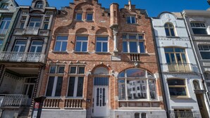 A historic building with a central arched entrance, large windows, and a brick facade.