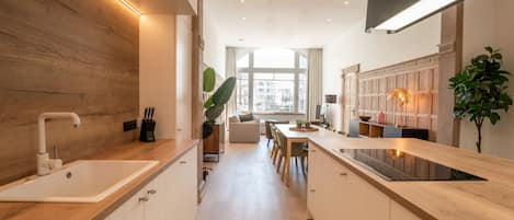 A modern kitchen with a central island, wooden cabinetry, and a large window providing natural light.