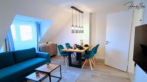 En moderne stue med en blå sofa, et spisebord med stole og et køkkenområde.