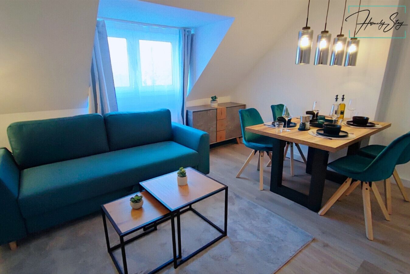 Ein modernes Wohnzimmer mit einem türkisfarbenen Sofa, einem Holztisch und einem Essbereich mit einem Holztisch und grünen Stühlen.