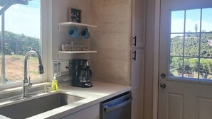 A kitchen with a sink, coffee maker, and a potted plant.