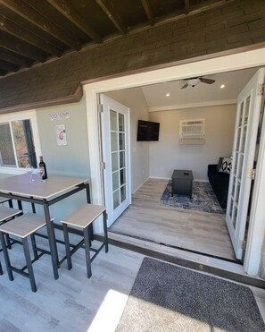 A cozy room with a wooden ceiling, a dining table with benches, a sofa, and a TV mounted on the wall. - Serene Vineyard Cottage Escape (Fallbrook)