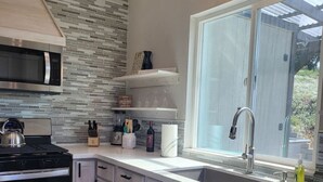 A modern kitchen with a large window, stainless steel appliances, and a patterned backsplash.