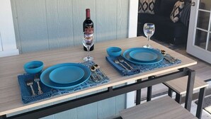 A dining table set with blue plates and wine glasses, a bottle of wine, and a sign reading 'PORCH THERAPY Session in Progress.'