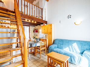 Een gezellig interieur met een houten trap, een zithoek en een blauwe bank.