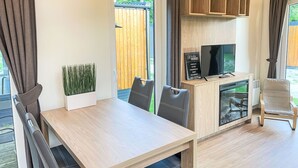 Eine moderne Küche mit integriertem Fernseher, Holzschränken und einem Essbereich mit Tisch und Stühlen.