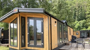 Eine moderne Holzhütte mit großen Schiebegläsern, einer Terrasse und Sitzgelegenheiten im Freien.