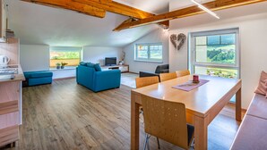 Un vaste espace de vie doté d’un plafond en bois, d’une table à manger et d’un canapé.