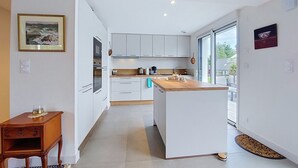 Eine moderne Küche mit weißen Schränken, einer Holzauskładung und Blick durch die Glastür.