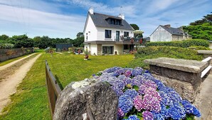 Ein modernes, zweistöckiges Haus mit großem Vorgarten, befestigter Auffahrt und einer Steinmauer.