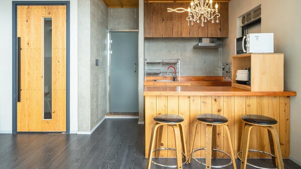 Una cocina moderna con armarios de madera, una zona con taburetes de bar y un microondas empotrado.