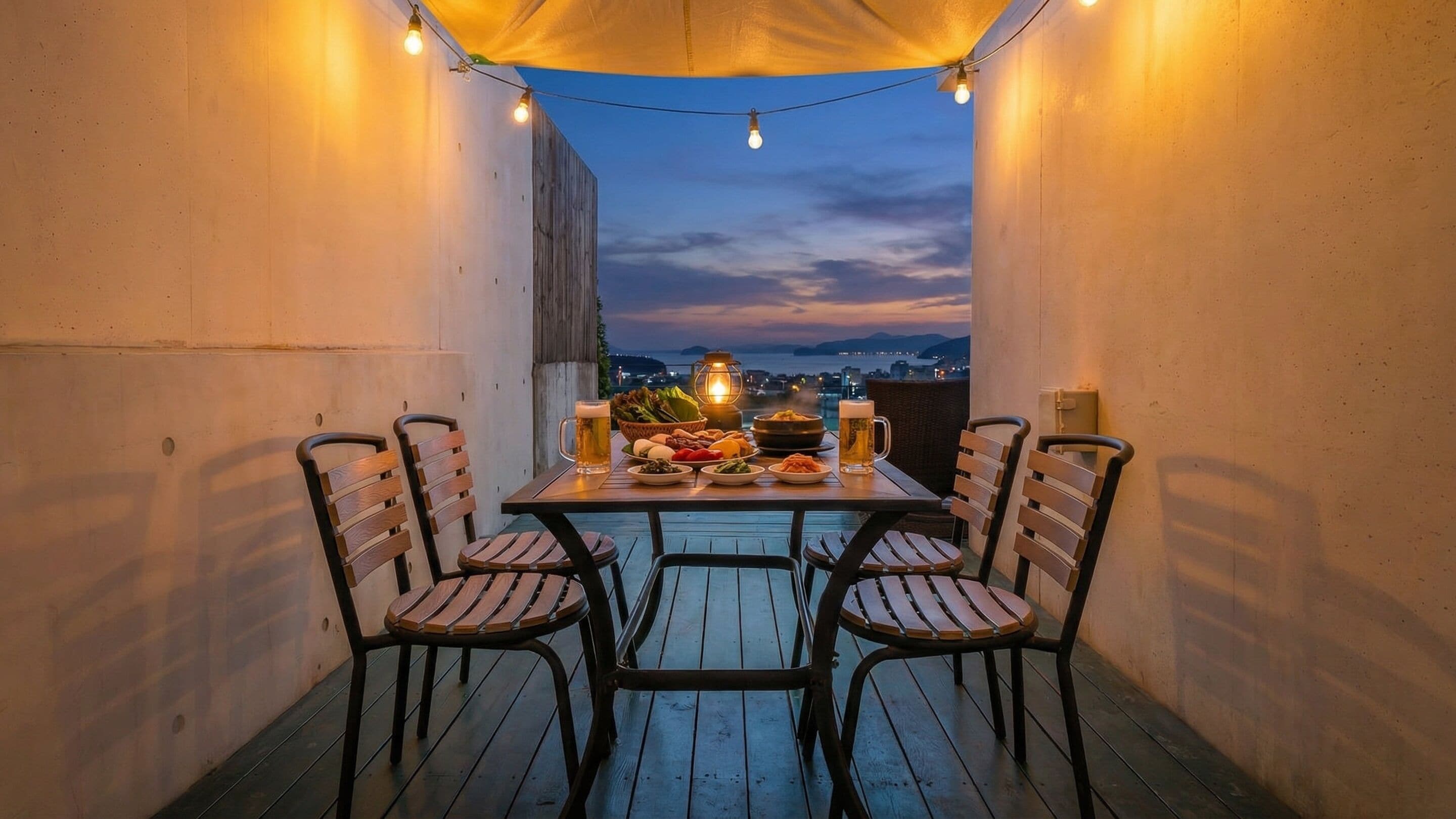 A dining table with four chairs, a lantern, and a view of the city at dusk.