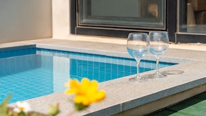 A swimming pool with two empty glasses on the edge, a yellow flower in the foreground, and a building with large windows in the background. - Geojedo Raonhiljo Pollvilla Pension (Geoje)