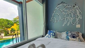 A hotel room with a large window, a bed with white bedding, and a decorative wall piece. - Seattle Samaesarn Resort (Sattahip)