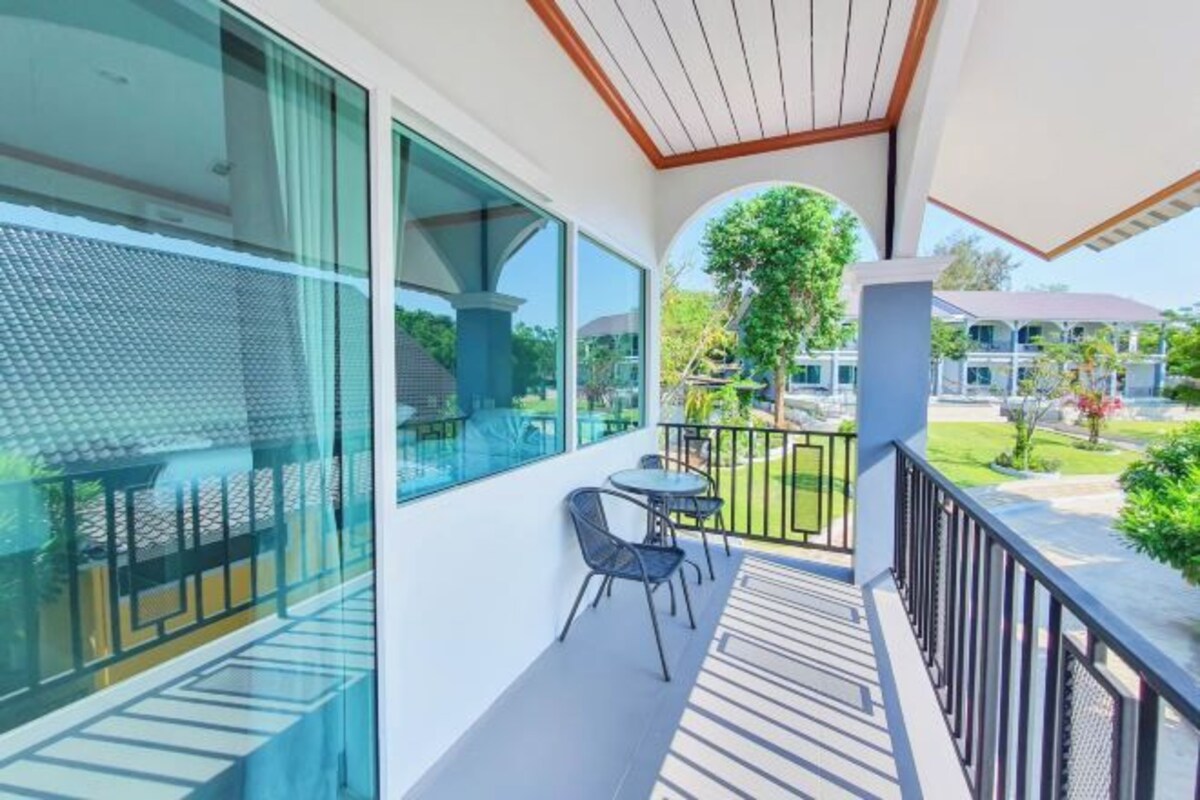 Un balcon doté d’une paroi en verre, d’une petite table et de deux chaises.