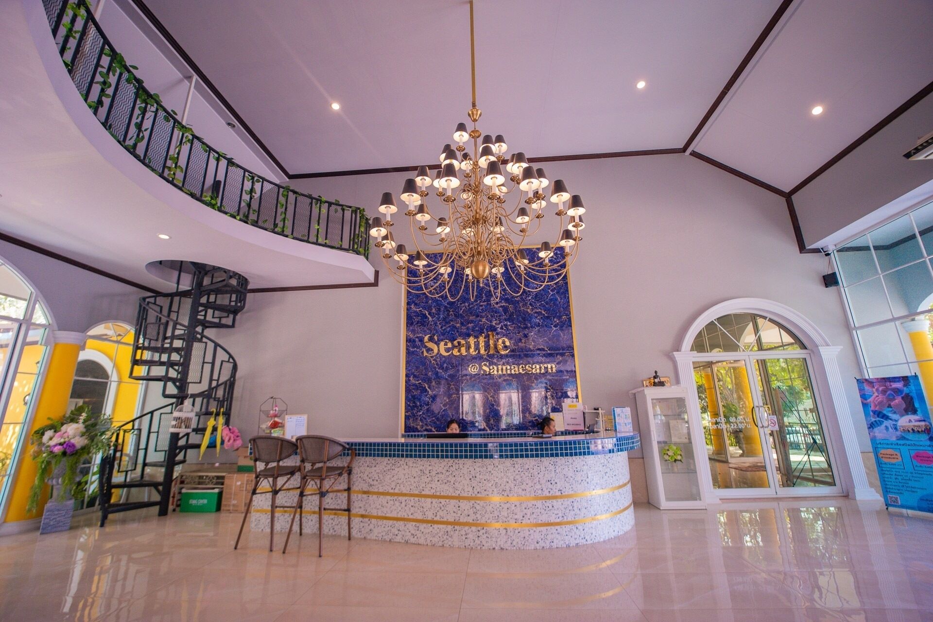 Un vestíbulo de hotel con un mostrador de recepción central, una araña de cristal y una escalera de caracol.