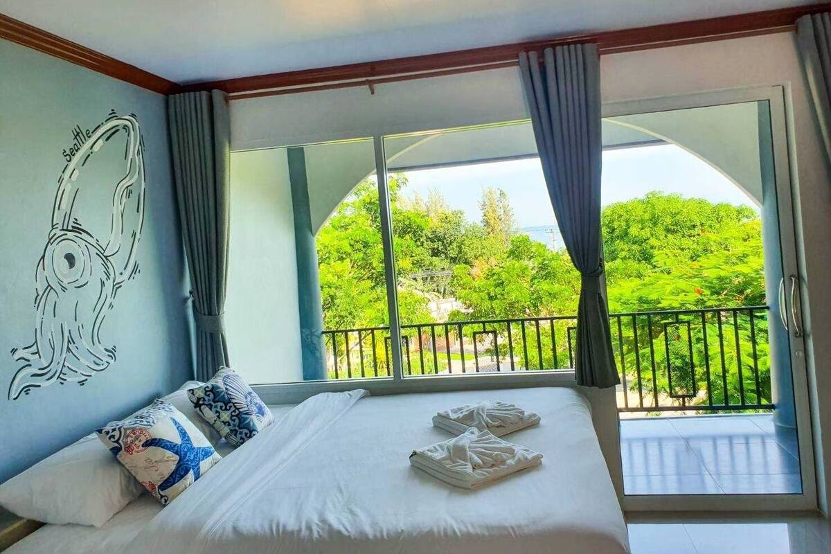 Habitación de hotel con una cama grande, vistas a zonas verdes y un balcón con barandilla.