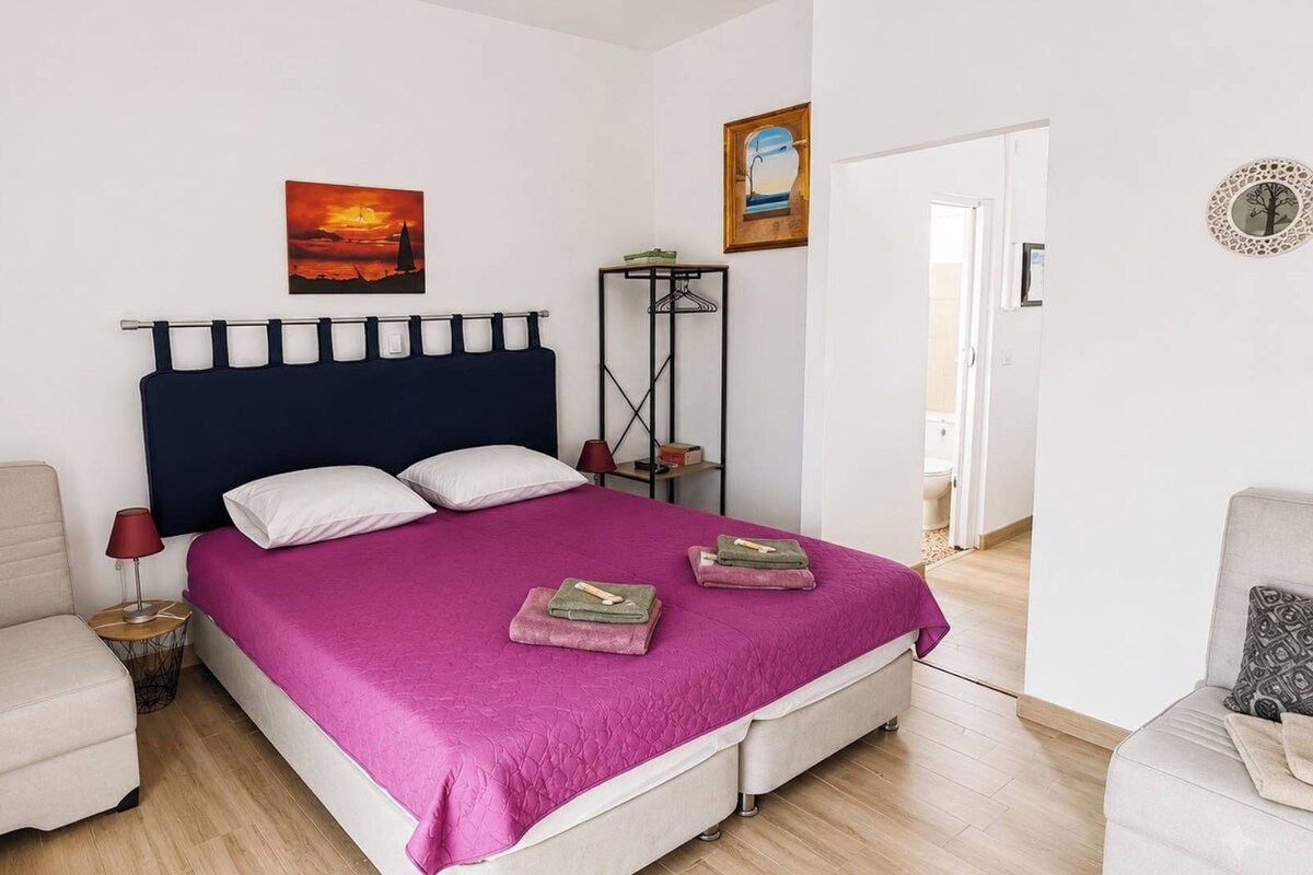 A bedroom with a bed, bedside tables, a chair, and a wardrobe.
