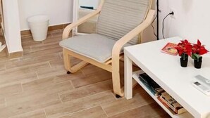 A small, neatly arranged room with a wooden floor, a white desk with a lamp, a chair, and a mirror. - Karavaki Apartments (Zakynthos)