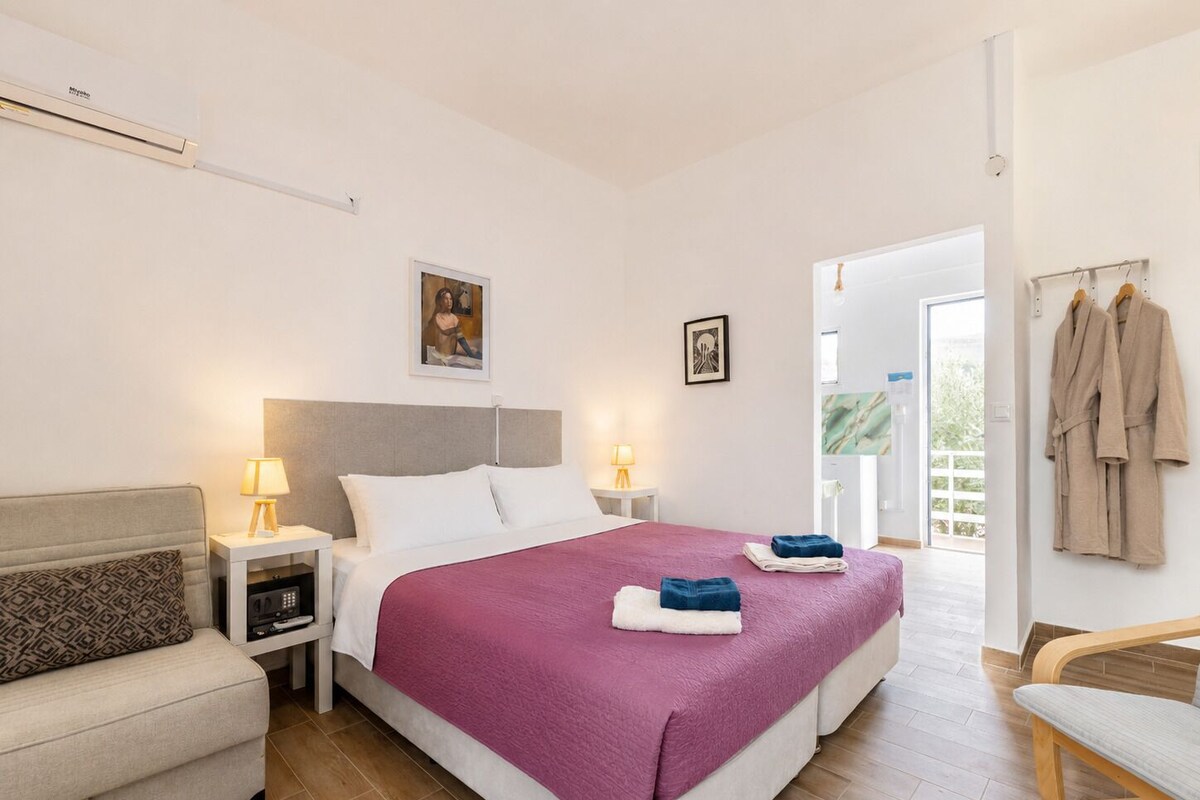A hotel room with a bed, bedside tables, a chair, a wardrobe, and a view of the outside.