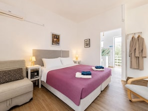 A hotel room with a bed, bedside tables, a chair, a wardrobe, and a view of the outside.