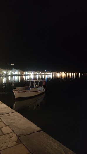 A nighttime view of a dock with a boat moored at the edge. - Karavaki Apartments (Zakynthos)