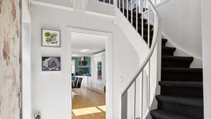 Una escalera conduce a un área de comedor con vistas a una cocina y un salón.