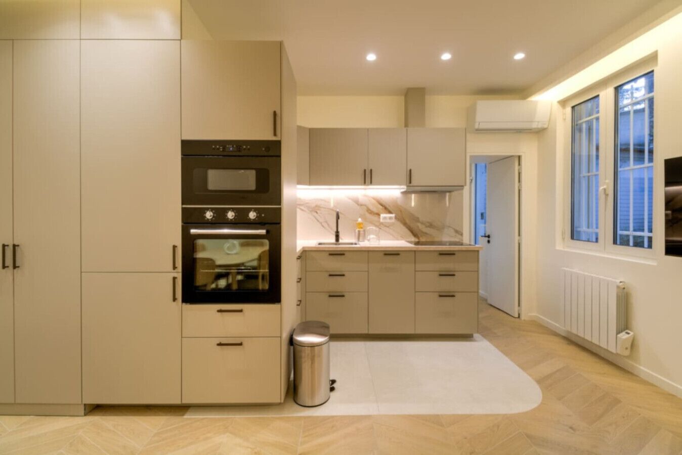 Una cocina moderna con horno integrado, pileta y basurero.