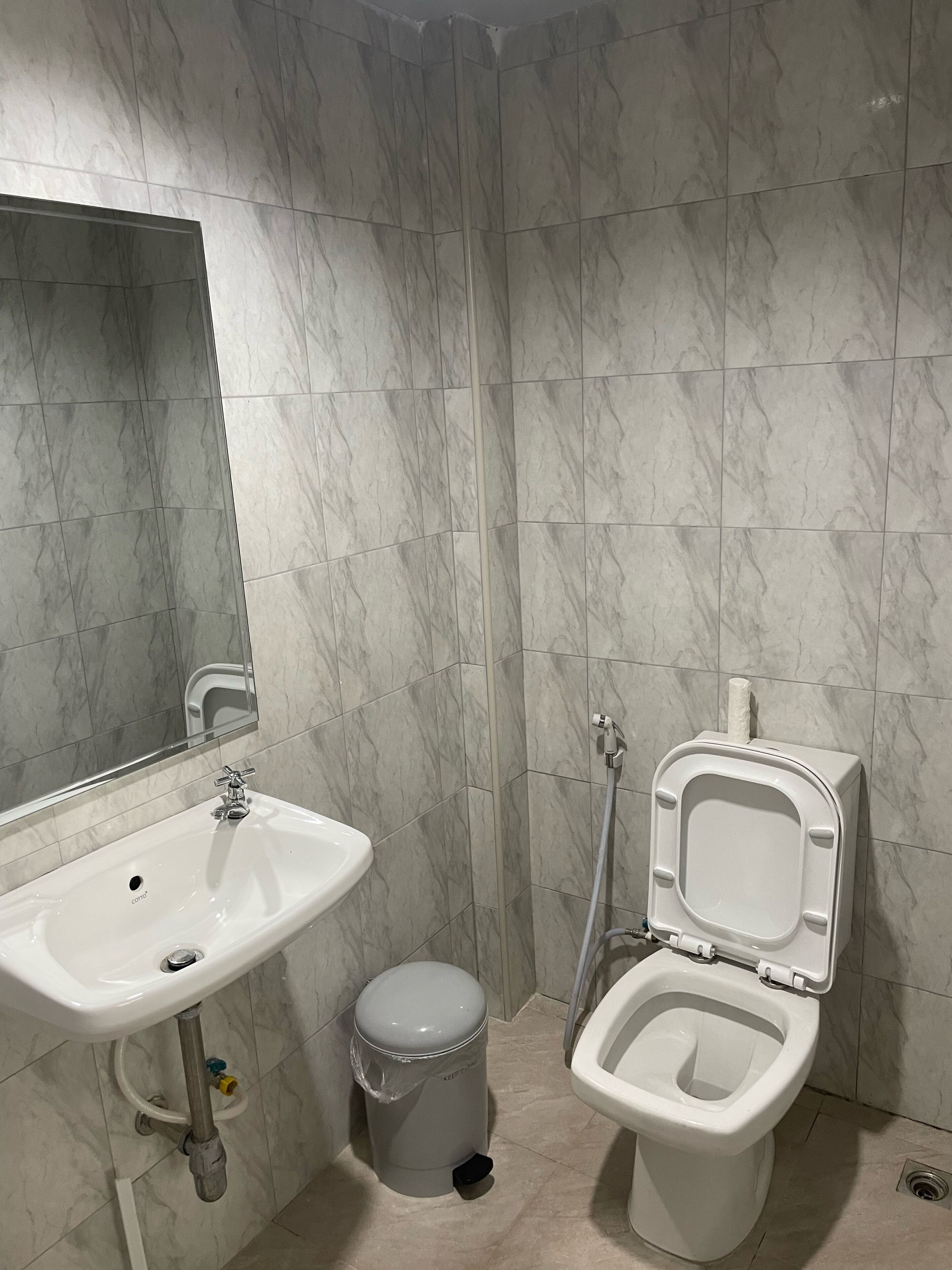 A bathroom with a white sink, a toilet, and a trash can.