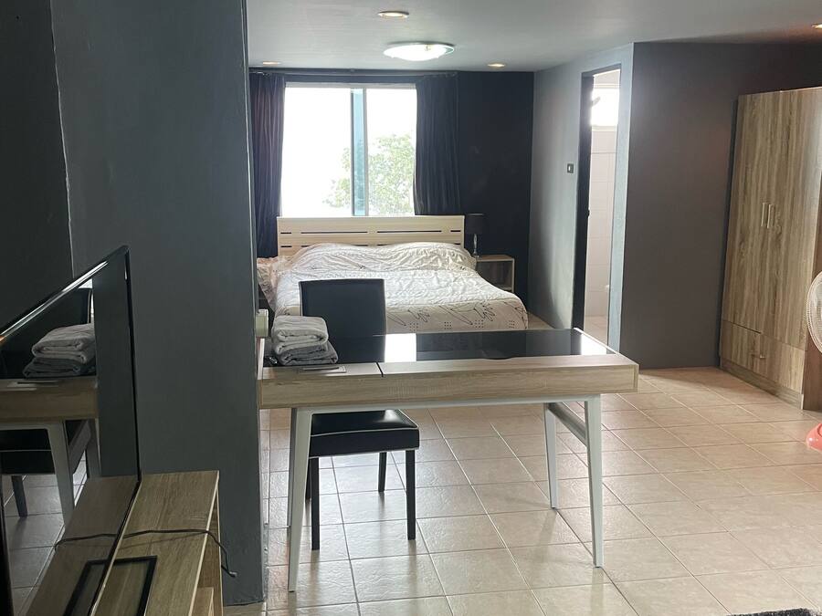 A modern bedroom with a bed, bedside table, and a desk with a chair.