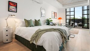 A modern bedroom with a large bed, a desk, and a balcony with a view. - Art Deco Retreat - Hot Tub|Parking (Collingwood)