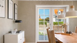 Un comedor con una mesa de madera, sillas, un armario blanco y un ventanal con vistas al exterior.