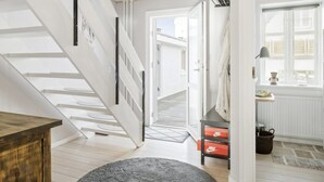 Un interior moderno con una escalera, un mueble de madera y una pequeña mesa con una lámpara.