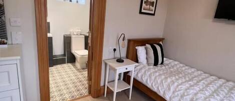 A bedroom with a bed, a small desk, a chair, and a wardrobe.
