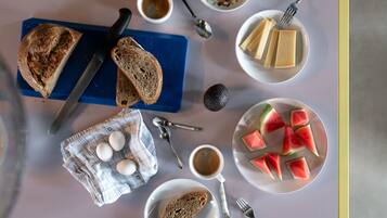 A breakfast setting with bread, eggs, coffee, and watermelon slices on a table.
