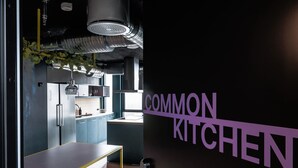 A modern kitchen with stainless steel appliances, a long counter, and a wall-mounted sign reading "COMMON KITCHEN". - Århus North 1BR Apartment by Daniel&Jacob's (Aarhus)