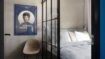 Una habitación de hotel moderna con una cama grande, una silla y un cartel en la pared.