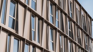 Un edificio moderno con una facciata beige e una griglia di finestre.