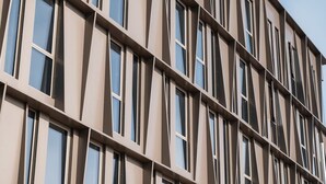 A modern building with a grid of windows and a beige facade.