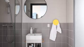 A modern bathroom with a shower, sink, and mirror.