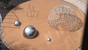 Un parque infantil con un arenero circular, estructuras metálicas y objetos esféricos.