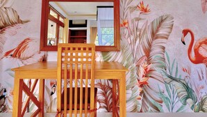 Een houten tafel met een stoel en een spiegel in een kamer met behang met bloemen.