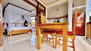 Een kamer met een bed, een eettafel met stoelen, een keukenhoek en een koelkast.