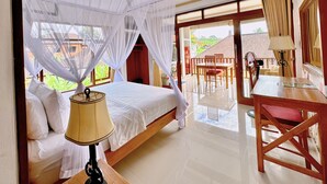 Een slaapkamer met een bed, een nachtkastje met lamp, een raam met witte gordijnen en uitzicht op buiten.