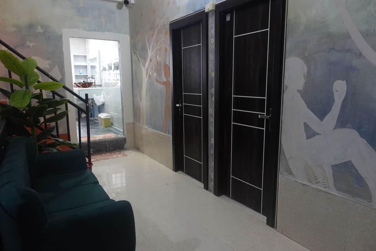 A hallway with a staircase, a green sofa, a potted plant, and a mural on the wall.